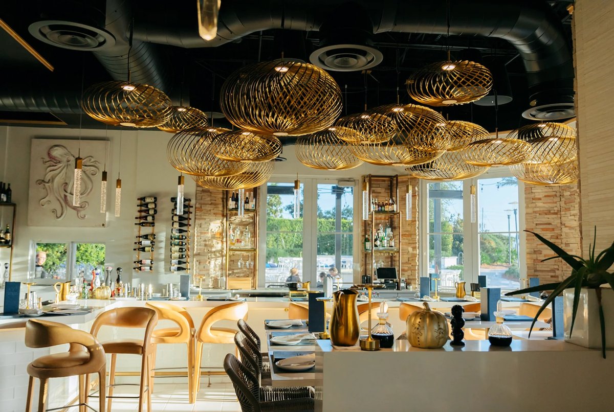 Dining room with gold woven pendant lights at Aja 30A in Inlet Beach, Florida