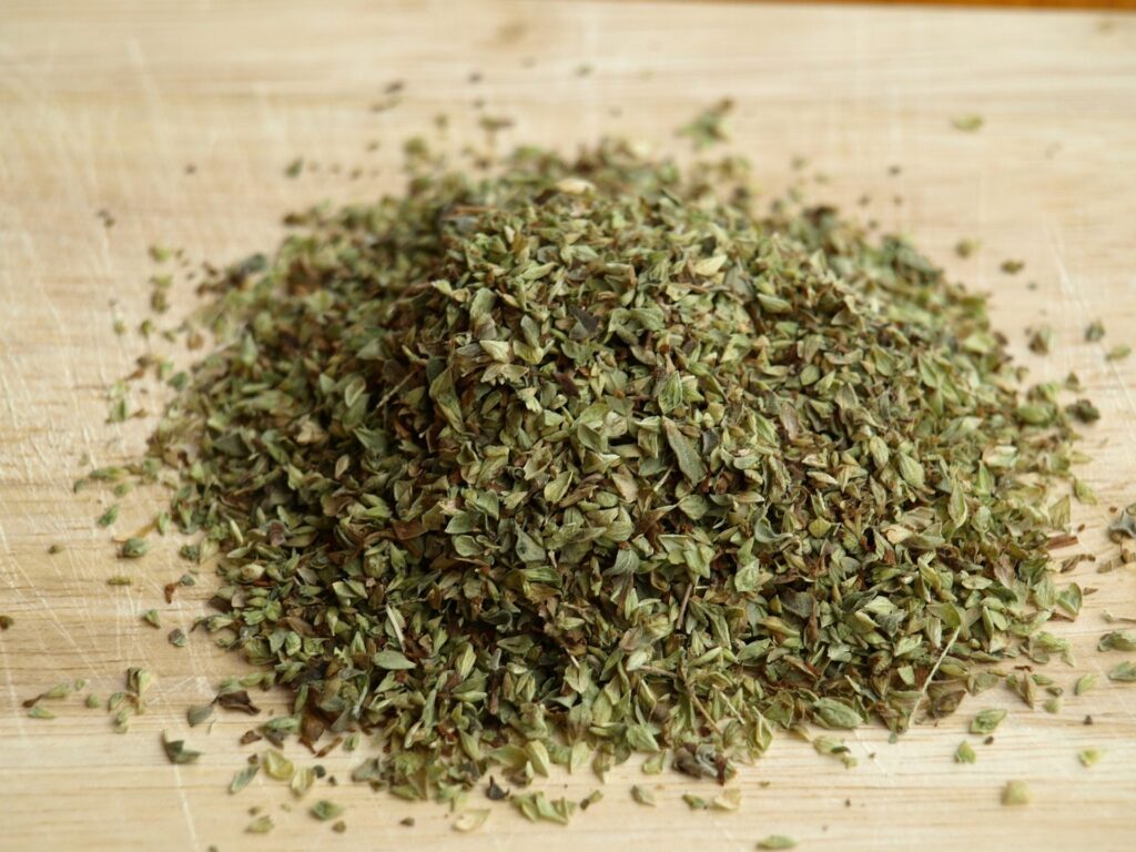 Pile of dried oregano leaves on a wooden cutting board