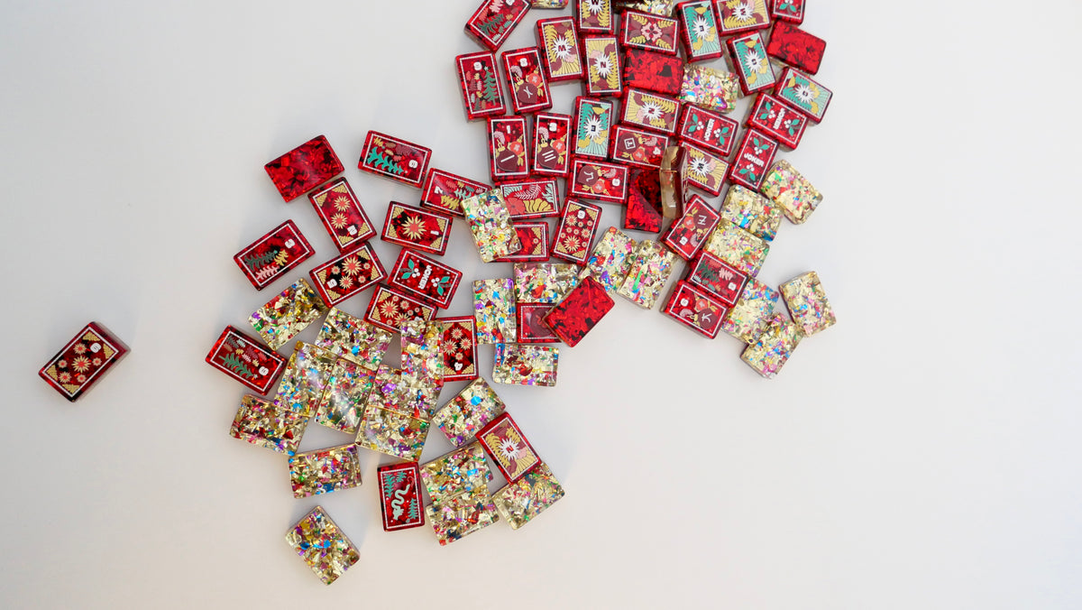 Mahj Pit Merry Merry holiday mahjong tiles in red and glitter scattered on a white table