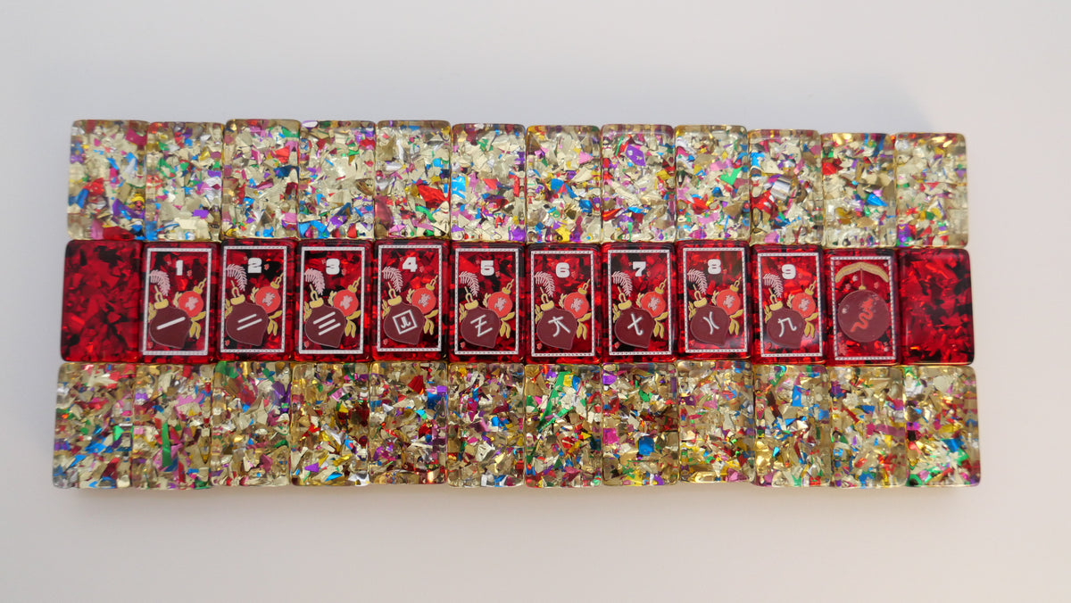 Row of Mahj Pit Merry Merry holiday tiles with red vintage-style faces framed by glitter confetti tiles