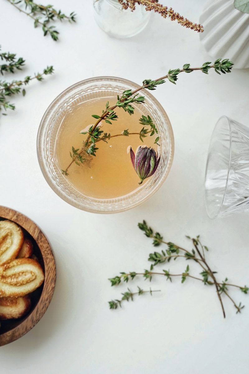 Fresh thyme sprig floating in a golden herb mocktail